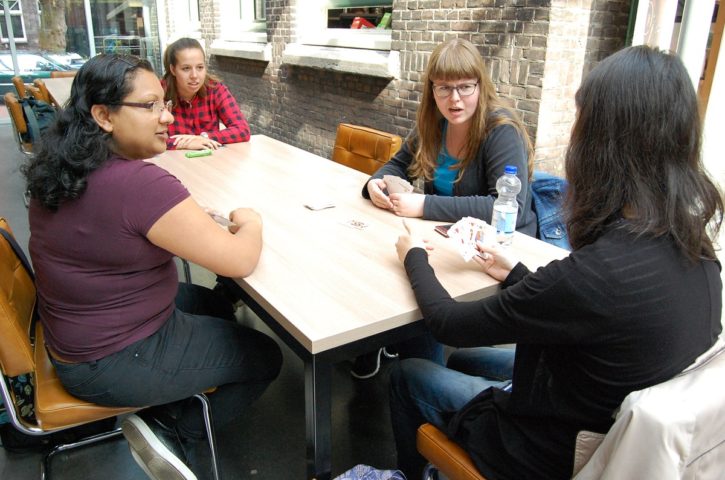 Foto waarop de drie studenten zitten te kaarten