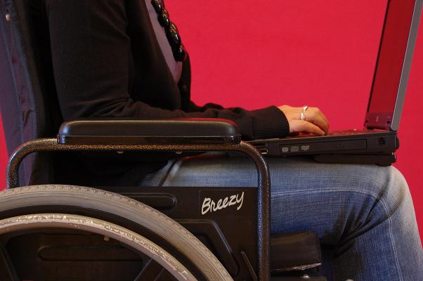 Gecropte beeld van een oud rolstoel met iemand erin met laptop op schoot