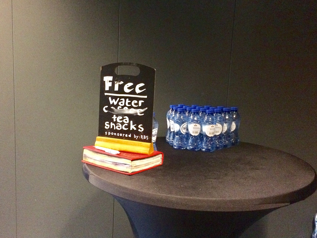Op een tafeltje staan flesjes water en een bordje met de tekst: Free coffee, tea, water