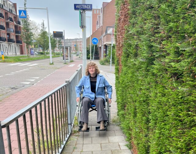 Larissa Schaap in een rolstoel op de stoep in Maassluis.