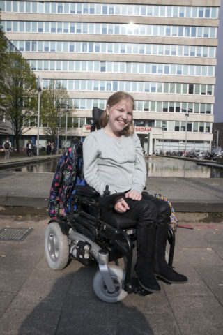 Vivian van Leeuwen in rolstoel voor gebouw hogeschool
