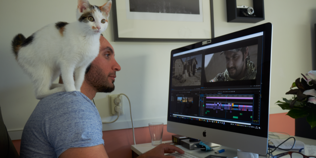 Haider met een kat op zijn schouder achter de PC