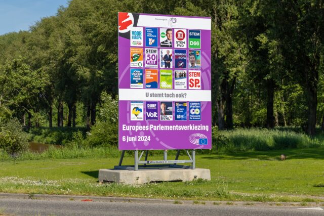 Bord met verkiezingsposters in groene omgeving